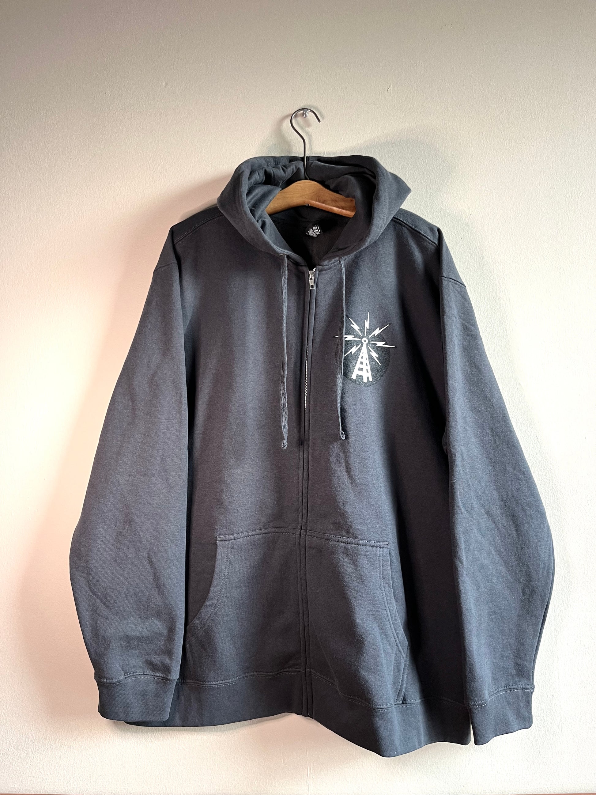 Charcoal gray zip up hoodie with KFAI transmitter logomark: white transmitter with black background.