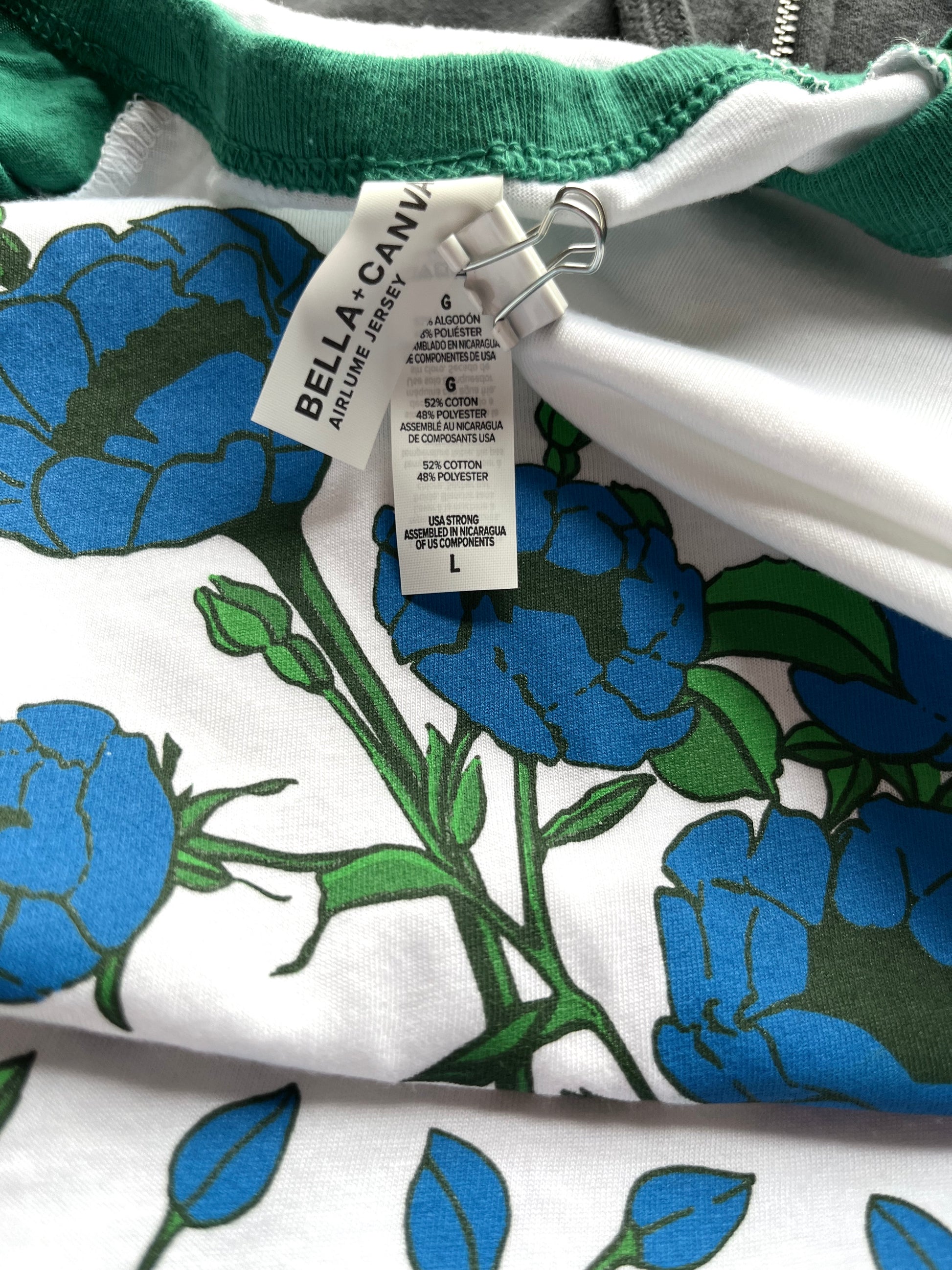 Close up photo of the garment tag: BELLA + CANVAS - 3/4 Baseball Tee (<span data-mce-fragment="1">52% Airlume combed and ring-spun cotton 48% poly, 40 single 3.6 oz</span>)